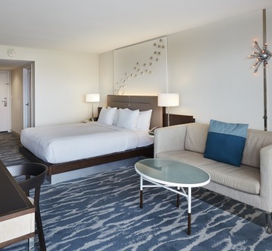 Room with King bed and small living area with couch and coffee table and desk